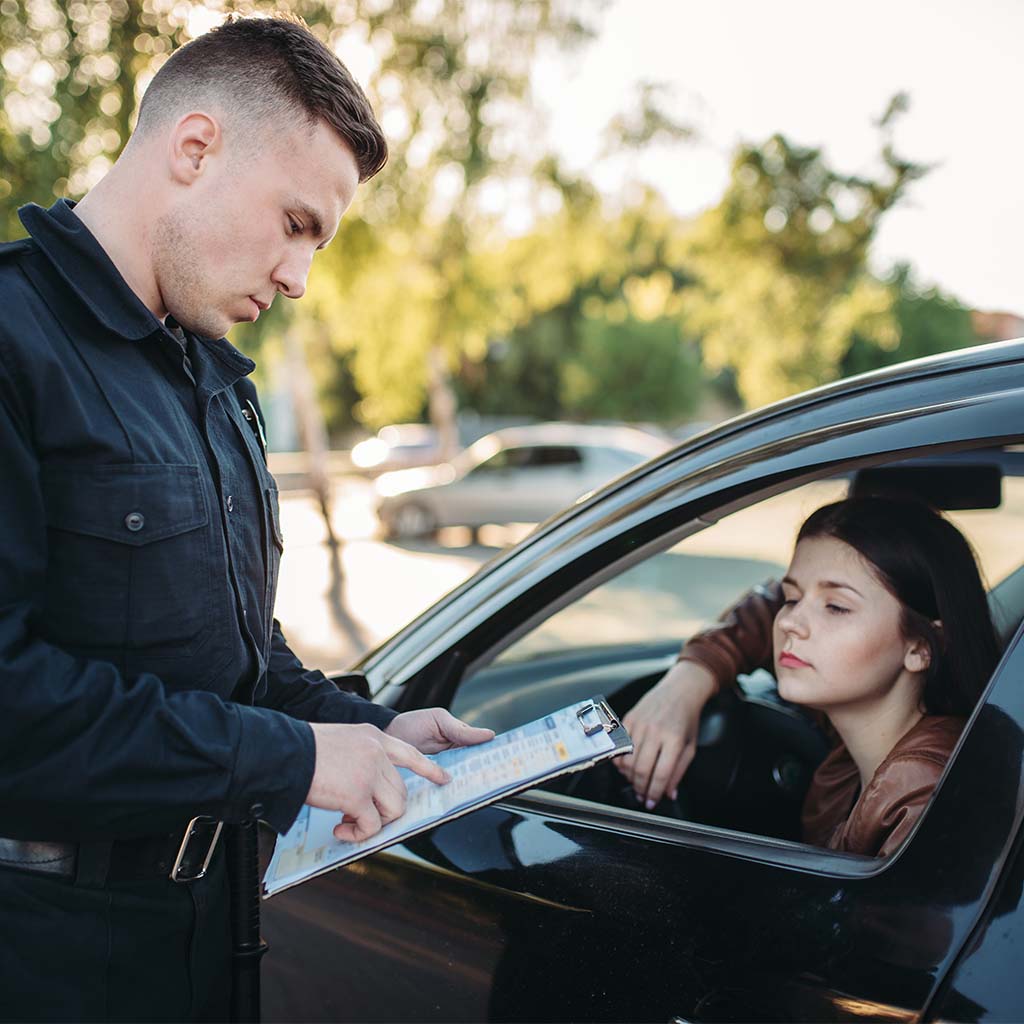 Police officer giving ticket to woman in car